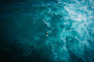 Topdown dronefoto van een surfer in turquoise zee