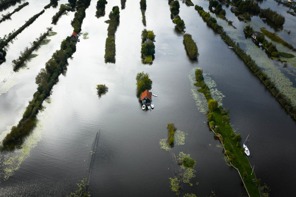 Dronefoto van een huisje op een eilandje tussen stroken land en water