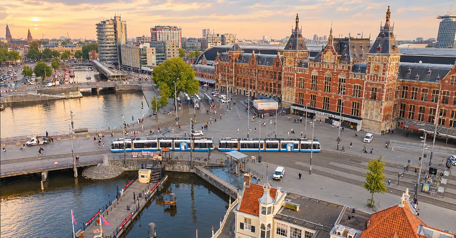 Dronefoto van Amsterdam Centraal en het Stationsplein bij zonsondergang