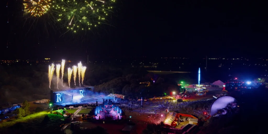 Dronefoto van vuurwerk boven het hoofdpodium van een festival in de nacht, buiten de UDP