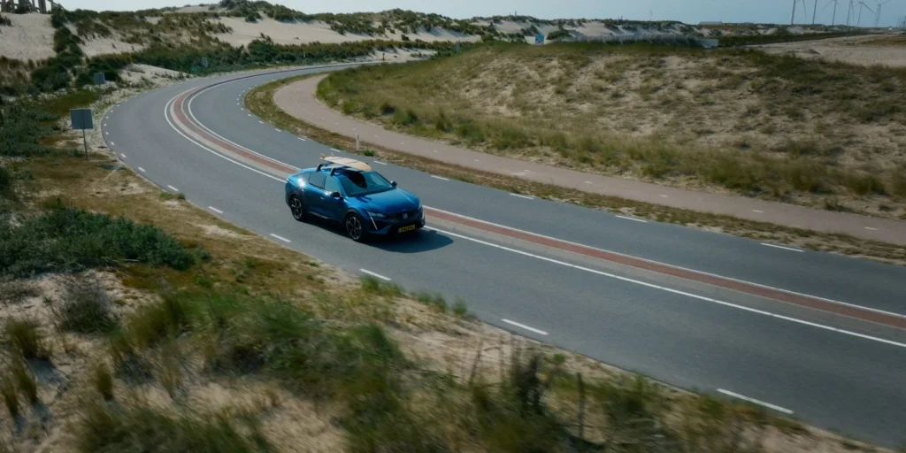 Drone opname van een auto met surfplank op een duinweg