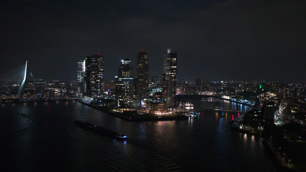 Dronefoto van de skyline van de Kop van Zuid met Hotel New York in Rotterdam in de nacht, buiten de UDP